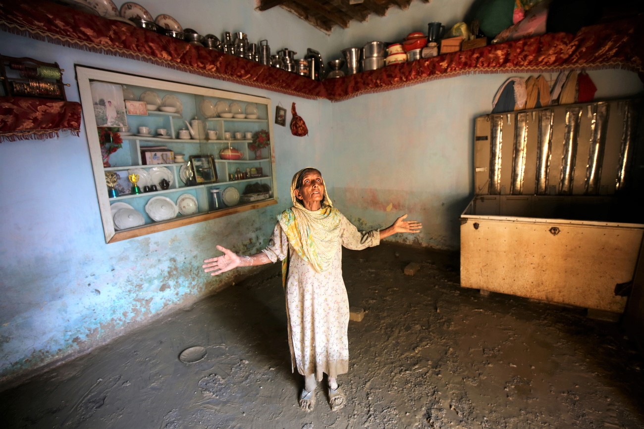 eine Frau in Pakistan breitet ihre Arme aus und blickt in ihrem Haus nach oben